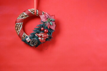 Holiday wreath with red ornaments, pinecone and poinsettia creating warm and peaceful Christmas atmosphere.