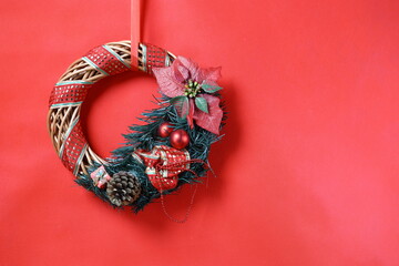 Minimal Christmas wreath composition on vivid red background expressing calm festive atmosphere and traditional holiday decor.