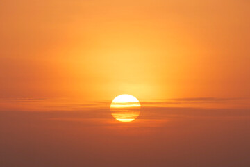 An orange sun setting on the horizon