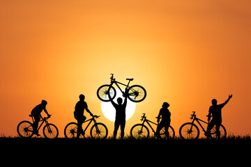 Silhouette of bikers with bicycles in the setting sun. Celebrating the joy of cycling with a bicycle held up high 