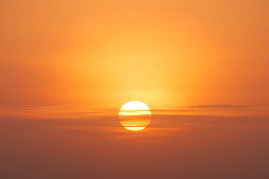 An orange sun setting on the horizon