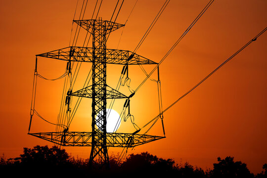 Silhouette of a high-voltage tower against a vibrant sunset, highlighting the infrastructure that powers our world