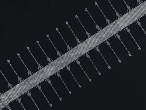 Aerial view shows a long, empty pier extending into still waters. The structure features evenly spaced supports, creating a pattern against the serene backdrop