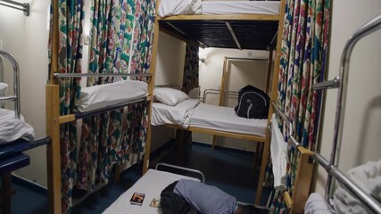 Bunk beds separated by floral curtains offer a degree of privacy and personal space within a shared hostel room, catering to budget travelers seeking affordable accommodation