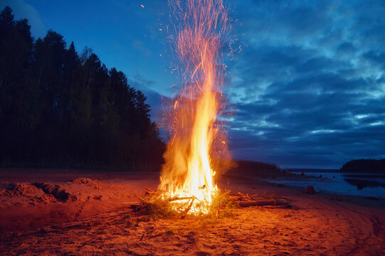 Bonfire on the riverbank at night.