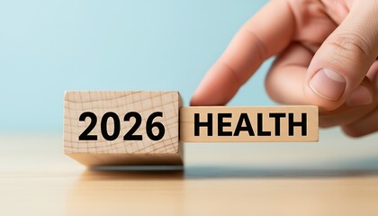 Hand placing wooden block with word health next to block with year 2026 symbolizing future healthcare planning or goal setting