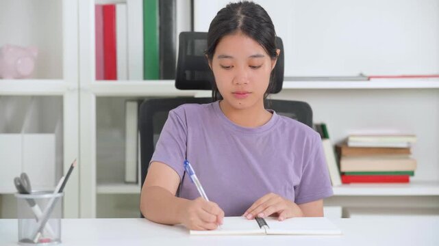 A cheerful woman sits at her desk with a laptop, ready to work or study from home