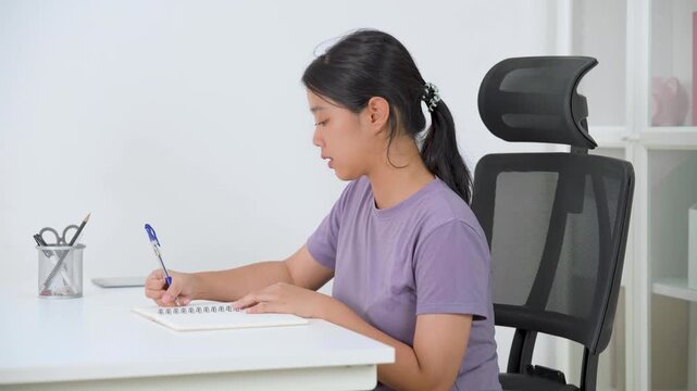 A cheerful woman sits at her desk with a laptop, ready to work or study from home
