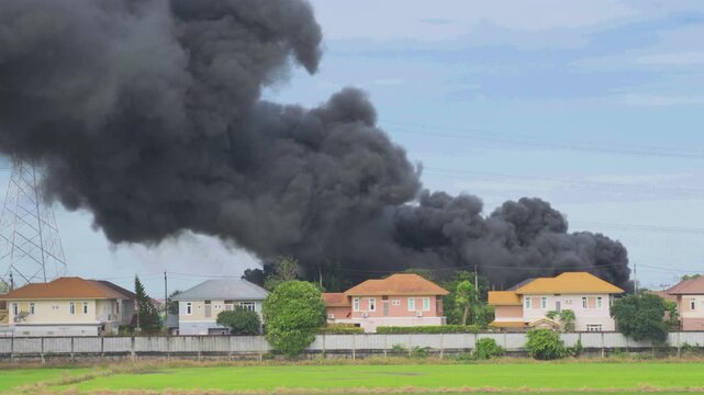 A large plume of smoke rises from an unseen source, threatening homes in the area