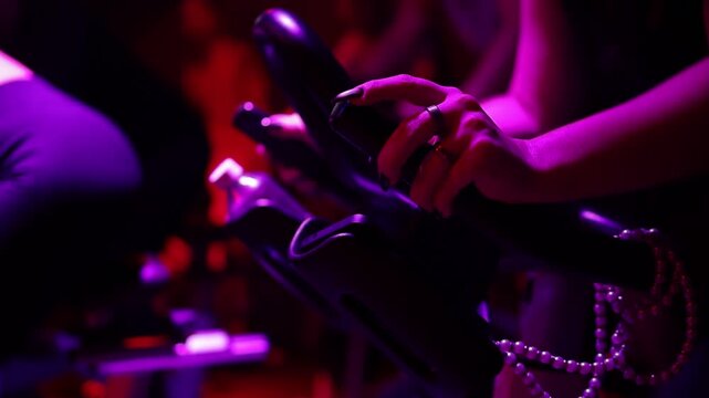 Cycle gym gear, Closeup of exercise bike with purple lighting and textured grips, Detailed view of spin bike handlebars and surroundings emphasizing fitness environment