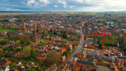 Historic Lichfield Cathedral near busy road and modern building crane
