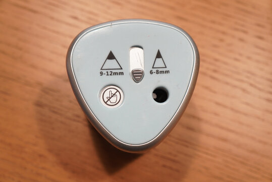 Close-up of an electric pencil sharpener with size indicators on a wooden surface