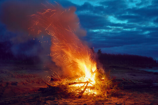 Bonfire on the riverbank at night.