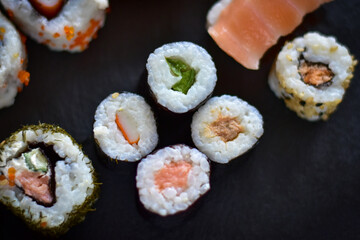 Fresh sushi rolls closeup on a black stone board, top view