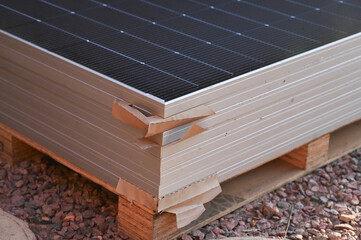 Solar panels are placed in an outdoor area on a wooden stand, awaiting setup. sustainable energy solution. stack of solar panels for use in renewable energy generation.