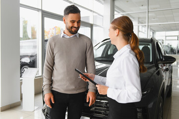 Car saleswoman advising client on new vehicle purchase