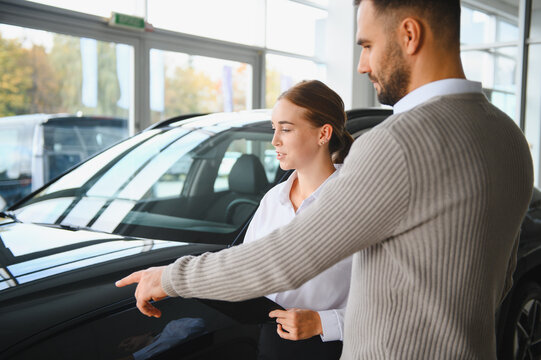 Salesman showing car features to female customer