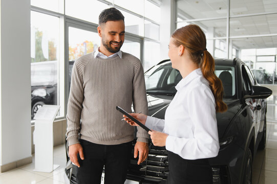Car saleswoman advising client on new vehicle purchase