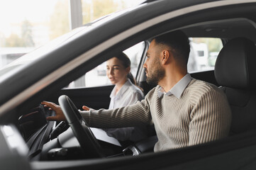 Customer test driving car examining features with saleswoman