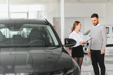 Saleswoman assisting male customer buying new car