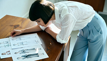 A female fashion designer working on clothing sketches in her studio. Creative professional reviewing illustrations for a new collection