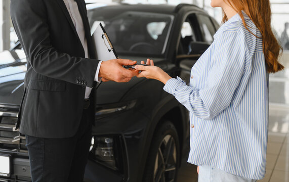 Car salesman handing over keys to new car customer