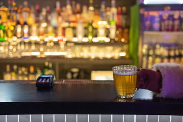 Santa Claus drinking beer at a bar. Close-up of a hand holding a mug of beer. 