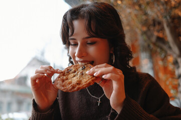 young woman eating pizza outdoors food blogger tasting cheesy slice at outdoor cafe, warm knit...