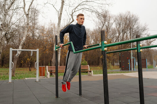 caucasian man performing dips on bars, mid-rep bodyweight strength training, controlled breathing, red shoes