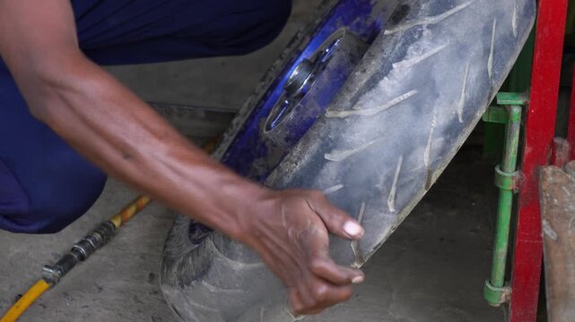 A mechanic make puncture repair on his garage.