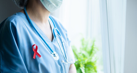 Female medical professional with red awareness ribbon on uniform, horizontal banner close up...