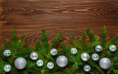 Fresh fir branches and silver balls on a dark wood background. New Year and Christmas decoration.