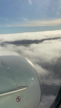 Vertical video. View from the window of an airplane descending through a dense layer of cumulus clouds.