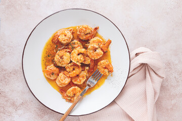 Savory shrimp dish served in a white plate with flavorful sauce and herbs