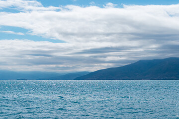 Calm seascape overlooking the Gulf of Argolis near Nafplio, with shimmering blue water and distant mountains under partly cloudy sky