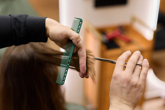 closeup of professional hairstylist at work, expert hands shaping and refining hair with precise tools