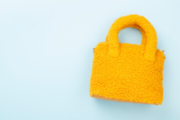 Fashionable yellow teddy bag on color background, top view