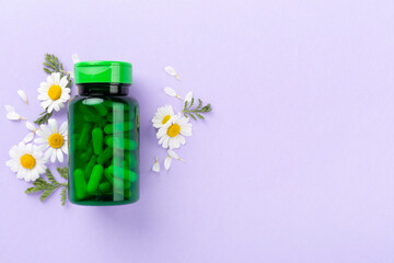 Fresh chamomiles with medicines on color background, top view