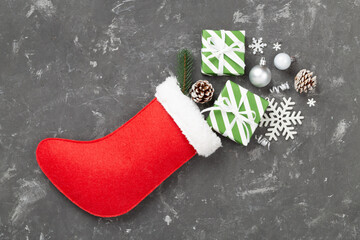 Christmas sock with gifts and decoration on concrete background, top view