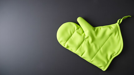 Green oven glove and potholder on dark textured table, top view. Space for text