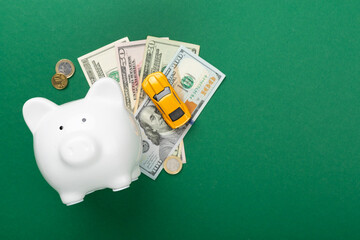 Piggy bank with money and model of car on color background, top view