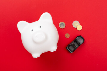 Piggy bank with money and model of car on color background, top view