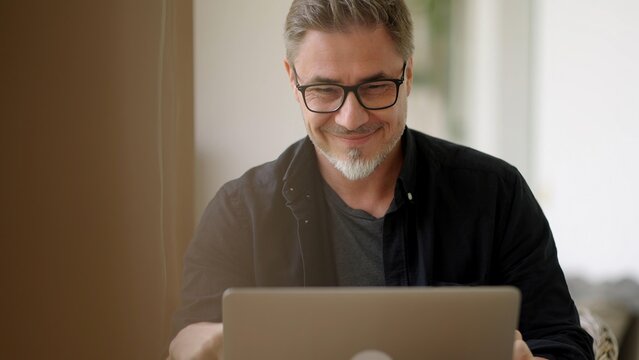 Businessman in home office. Middle aged man working with laptop computer at home outdoor on terrace. Online work, happy, smiling. - Powered by Adobe