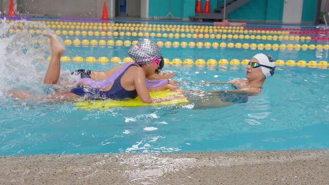 Children learning to swim with a kickboard and a coach