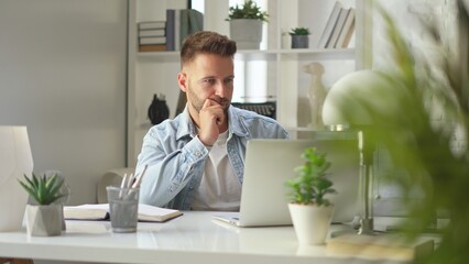 Businessman in casual using laptop in home office, Young adult man sitting at desk in study room, working online with computer, browsing the Internet.