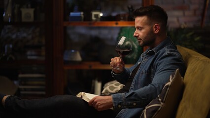 Man sitting in dark room at home drinking tasting wine, relaxing.