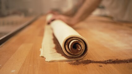Baker working with handmade pastries in small bakery. Cocoa snail roll, chocolate roll. Closeup photo of n ot staged, authentic moment.