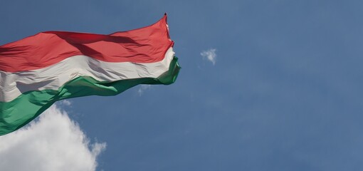 National flag of Hungary against the clear blue sky. This is the flag in front of the building of the Hungarian Parliament.