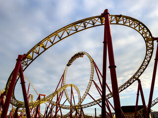 Rollercoaster ride structure thrill complex loop track against blue sky.