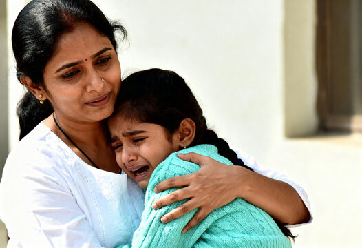 Indian mother comforting her crying daughter with a hug. A loving parent offers emotional support to her sad child. Motherhood and family care concept
